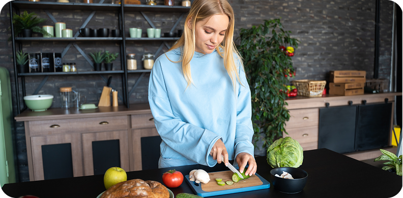 A woman chopping vegetables in a cozy kitchen.