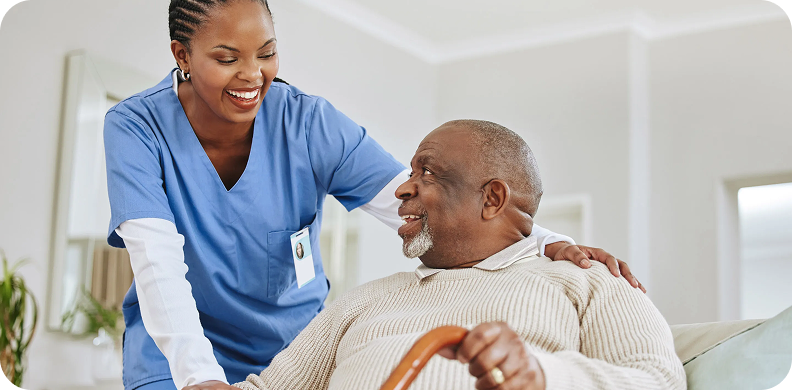 Nurse warmly assisting an elderly man with a cane.